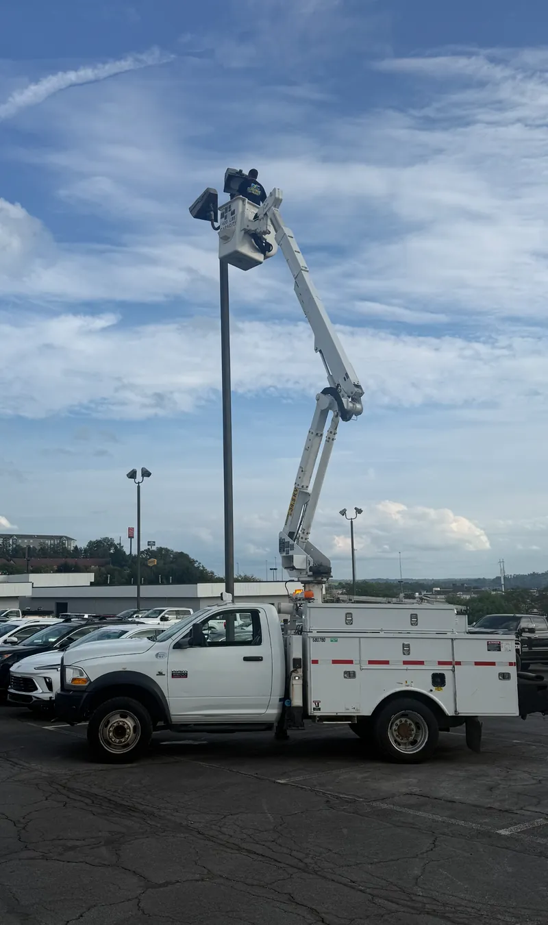 The DC Electric bucket truck with the bucket raised to a parking lot light