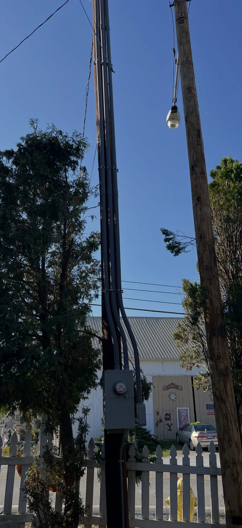 A utility pole with a new service drop and a light, against a blue sky