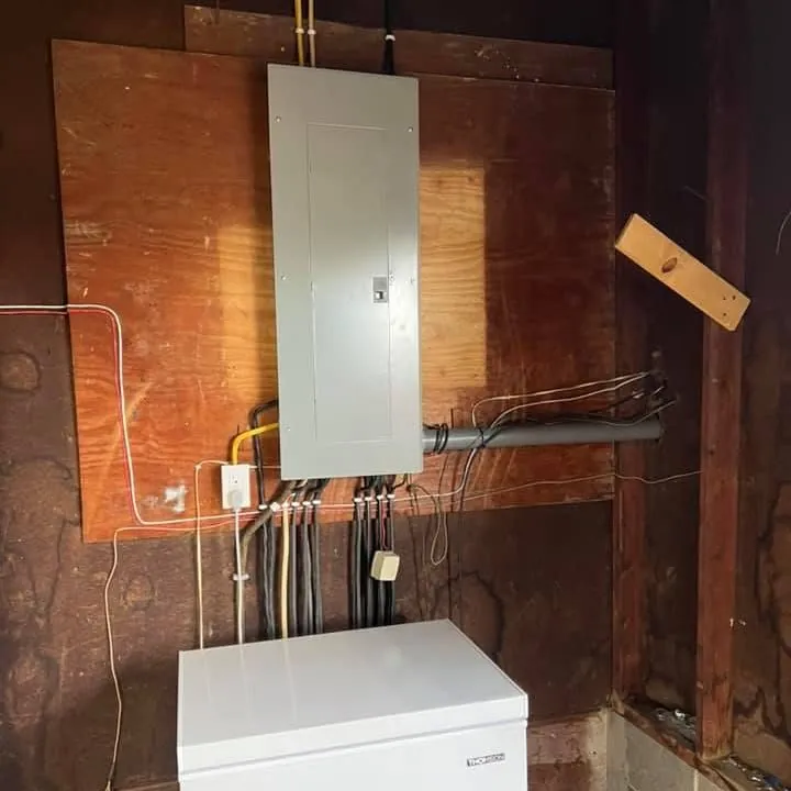New electrical panel mounted on plywood with tidy conduit, installed by DC Electric