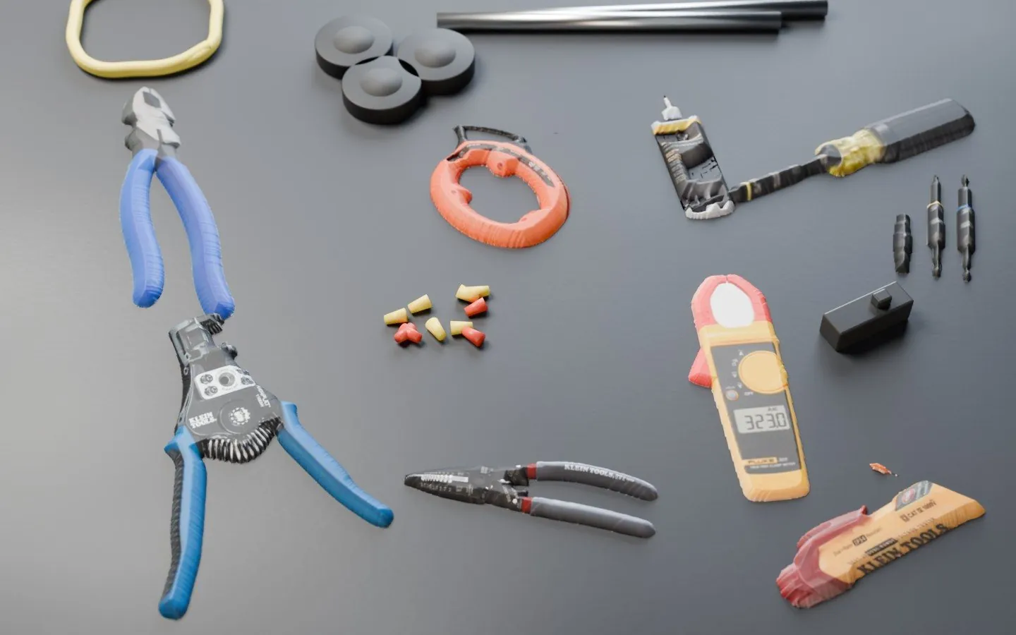 Electrician tools on plywood: Klein wire strippers, Klein Katapult strippers, Klein lineman's pliers, a Fluke 323 clamp meter, a Klein NCVT-2 voltage tester, an 11-in-1 screwdriver, fish tape, wire nuts, electrical tape, Romex and EMT